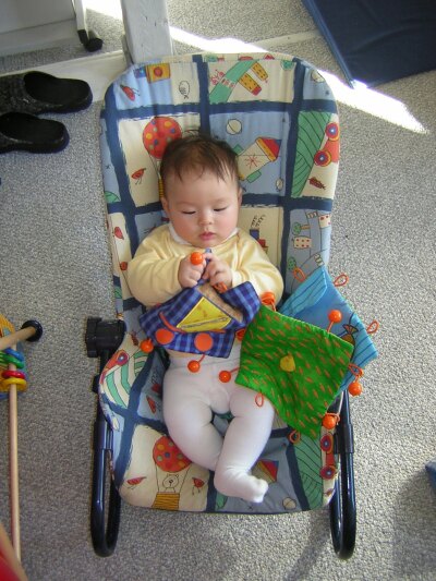 Katja spielt in der Babywippe mit dem Stoffbuch